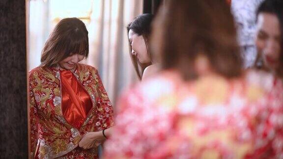 在婚纱店亚洲的中国新娘在姐姐的帮助下一边看着镜子一边试穿中国传统的婚纱