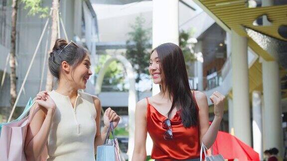 亚洲美丽的两个女人在百货公司购物户外商品迷人的年轻女性朋友拿着购物袋然后快乐地走在购物中心享受购物