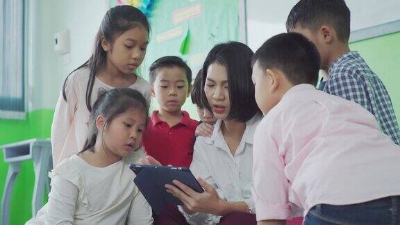亚洲教师在课堂上使用平板电脑给学生提供在线材料