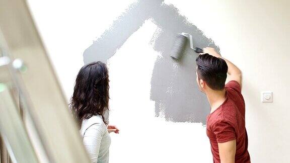 年轻夫妇画墙在房子形状