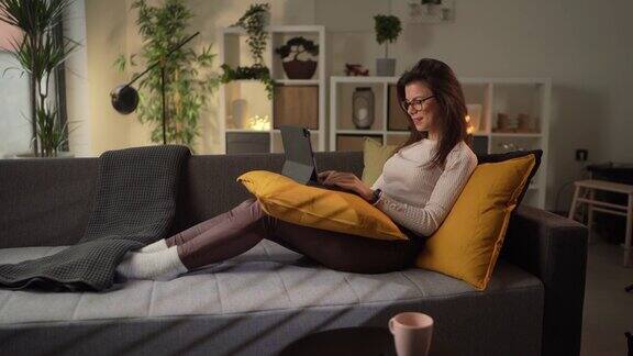 漂亮的女人坐在客厅的沙发上使用平板电脑