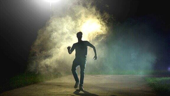 在黑暗的背景中一个男人在烟雾中奔跑慢镜头