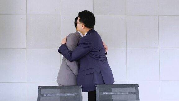 两个商人在会议室互相握手、拥抱