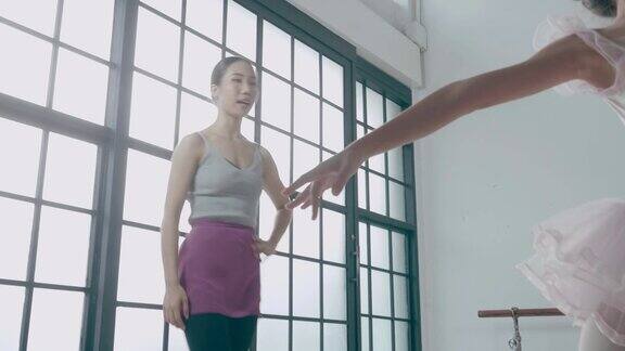 芭蕾舞教练在舞蹈工作室用积极的情绪教可爱的混血女孩