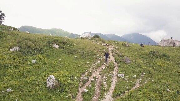 女人走在山间小径同时徒步旅行的无人机视图