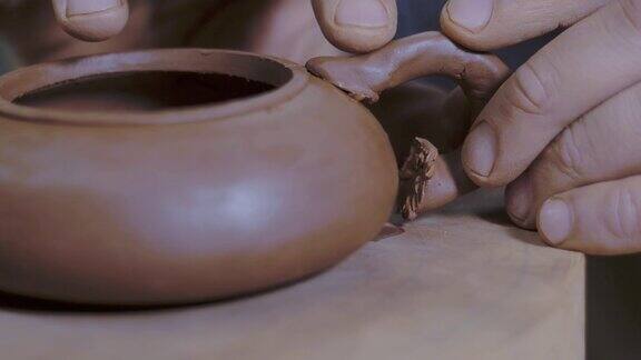 师傅将茶壶的手柄与宜兴陶制茶壶底座连接起来中国茶道用的茶壶4k的视频59.94帧秒