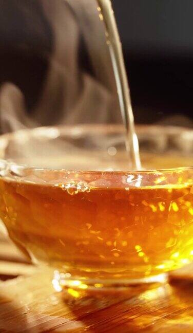 垂直视频草药中国茶倒入美丽的透明玻璃背景烟雾来自香味棒背光温暖的光茶道东方杯特写认不出来的人