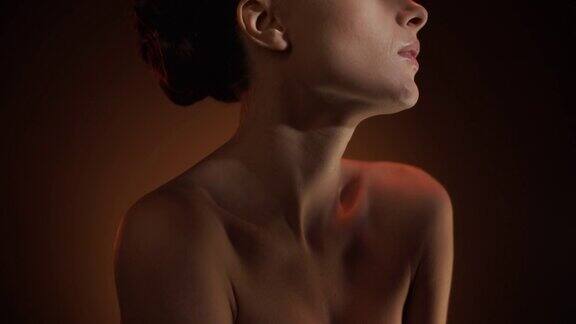 一个美丽的女性身体的特写:脸肩膀胸部在一束光
