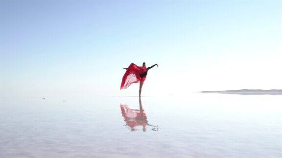 芭蕾舞演员在湖上用红色薄纱跳舞