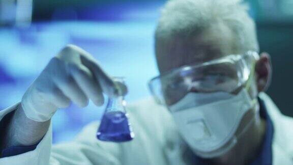 科学家在安全玻璃上检查烧瓶中的化学试剂特写镜头