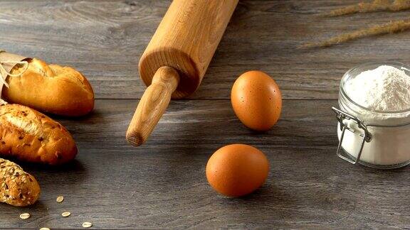 在木桌上放着长棍面包、鸡蛋和面粉