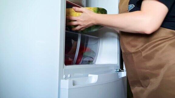 一个女人把切好的新鲜西瓜放在冰箱的架子上真实的生活方式家庭烹饪准备有机食品