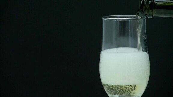 香槟与泡沫倒进一个玻璃在黑色的背景