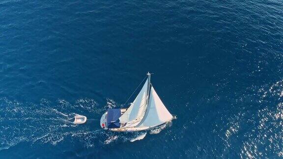 4K无人机实时拍摄宁静、阳光明媚的蓝色海洋上的帆船