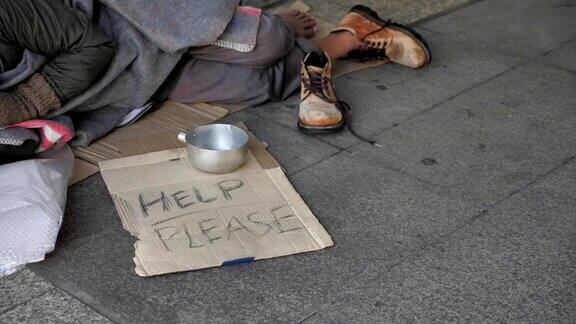 一个穿着脏衣服睡在街上寻求帮助的无家可归的老人