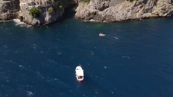 一艘红船的航拍视频背景是阿马尔菲海岸Furora峡湾的石拱桥