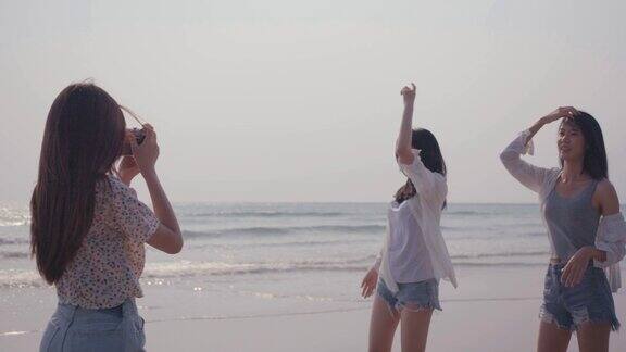 微笑快乐的一群年轻女子带着相机与朋友在海滩上自由跳舞暑假日落的人的生活方式
