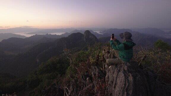 女徒步旅行者用智能手机在山上拍照