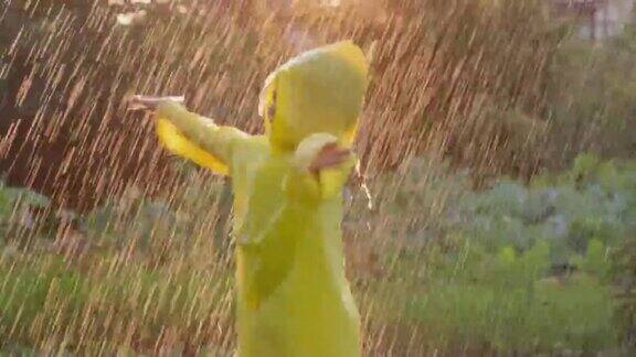 快乐可爱的小男孩举起双手穿着黄色雨衣享受着快乐的雨孩子在夕阳下玩雨滴快乐家庭夏天秋天秋天童年梦想概念4K