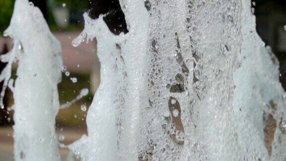 在夏天在公园阳光喷泉溅水的光的特写花园里的喷泉超级慢动作