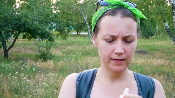 有花粉过敏症状的女性用鼻子闻空气站在夏季的自然背景下生病的小女孩打喷嚏用手帕擤鼻子用鼻喷雾剂治疗过敏性鼻炎