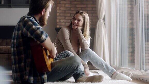 一个男人在家给女朋友弹吉他