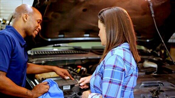 机械师在汽车修理店向客户讲解汽车维修