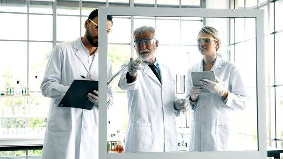 一组在实验室工作的化学家在玻璃显示器上做笔记和书写