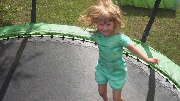 一个快乐的小女孩在后院的蹦床上蹦蹦跳跳
