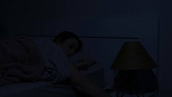 年轻女子躺在床上开着灯玩手机