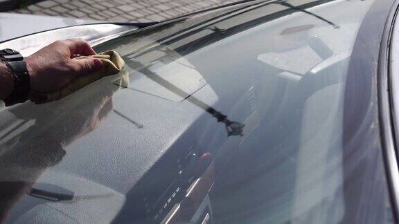男子用海绵和泡沫清洗汽车挡风玻璃汽车服务洗车他正在擦拭那辆白色汽车的玻璃和车身工人在外面洗车