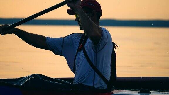 日落时分一个男人在划着皮划艇