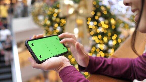 女士使用智能手机绿色屏幕在购物中心水平