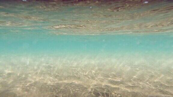 水下沙质海底水波搅动着沙子一片沙滩阳光穿过海洋抽象背景蓝绿色慢动作无缝循环