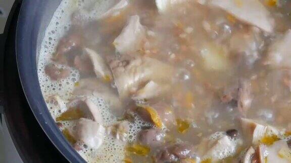 用勺子在平底锅中搅拌沸腾的蘑菇汤配上胡萝卜、月桂叶、土豆和香料近距离观看