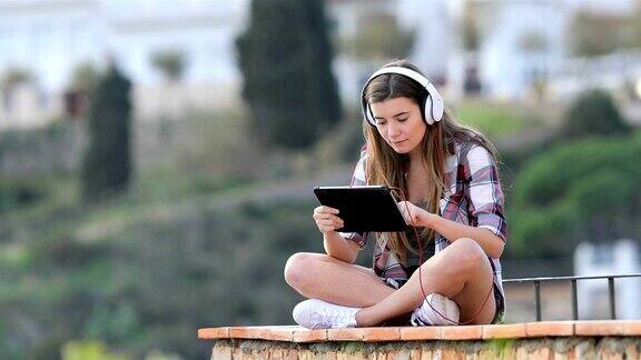 十几岁的女孩在平板电脑上看和听在线内容