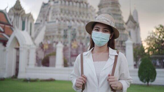 戴着口罩的亚洲女性游客正在泰国曼谷的阿伦寺旅行