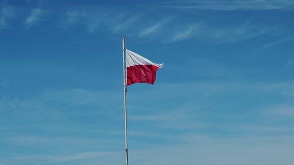 波兰国旗在风中飘扬蓝色的天空波兰的白色和红色旗帜