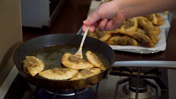 厨师用手在热煎锅里翻炒蘑菇饺子金黄酥脆的饺子在油里煮