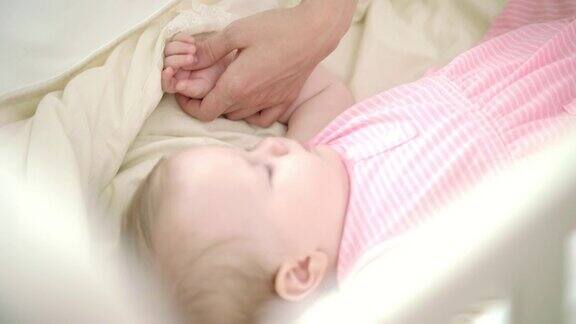 小女孩睡在床上母亲用手抚摸着熟睡的孩子