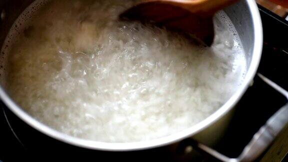 在不锈钢锅中加入开水用木勺将米饭混合