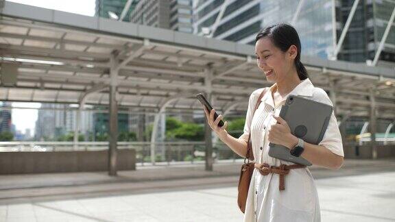 一名亚洲女性在城市中行走并使用智能手机