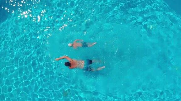 一个男人和一个男孩在一个透明的游泳池游泳的俯视图