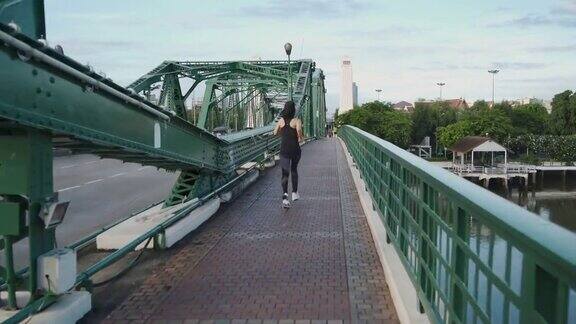 亚洲年轻女子在城市大桥上跑步
