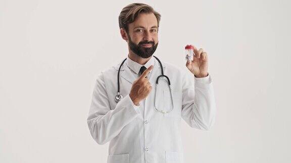帅哥医生拿着听诊器微笑着用手指指着瓶子里的药丸