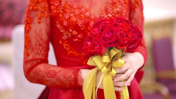 婚礼当天新娘身着红色婚纱手捧玫瑰花束