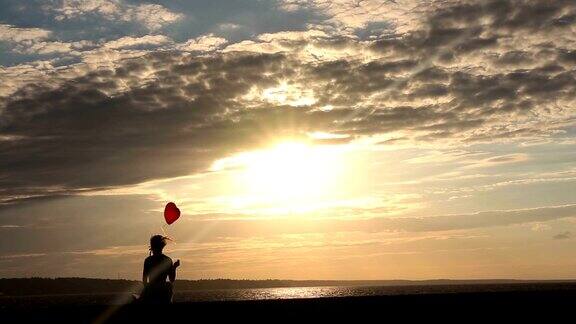 孤独的女人用心气球看日落