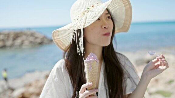 年轻的中国女游客微笑着自信地在海边吃冰淇淋