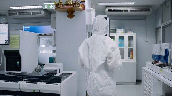 科学家们穿着防护服在无菌室里拿着血液试管在实验室里行走