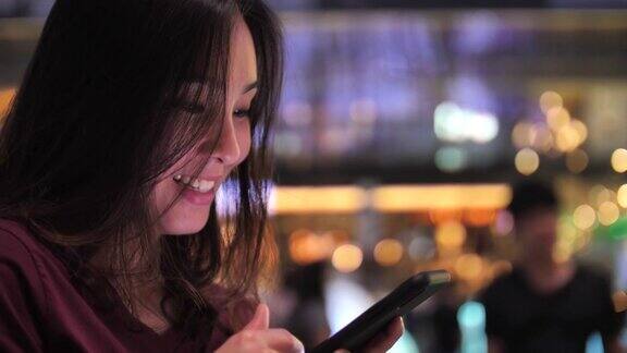 在城市生活中一个女人在晚上用智能手机社交媒体